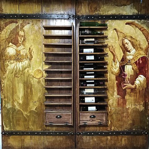Nephilim — White Wine, Red Wine: two painted wooden doors with iron strap hinges; each has a narrow wine rack and drawer built in; an angel in white holding an amber sphere on the left door, an angel in red pouring wine with a glass wine thief on the right door