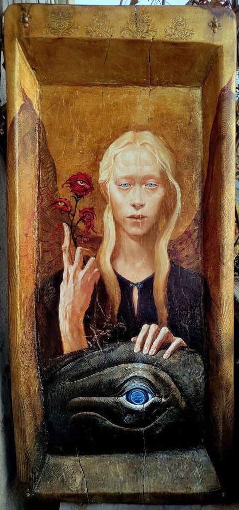 Angel: a pale, fair-haired angel in a dark robe on gold leaf, inside a carved and gilded hollow of wood; one hand holds a stem of red roses with eyes, the other rests on a large dark eye with a blue iris at the bottom